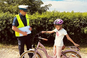 Uczennica pokazuje policjantowi wyposażenie roweru