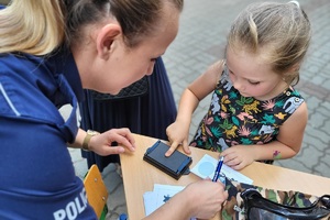 Dziewczynka odciska swoje linie papilarne na pamiątkowej kartce