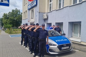 Policjanci stoją wzdłuż radiowozu, oddają honor