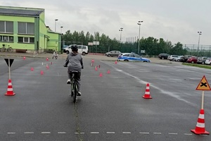 Uczeń jedzie rowerem po placu szkolnym