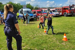 Policjantka obserwuje dzieci pokonujące slalom