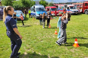 Policjantka prowadzi konkurencje dla dzieci, które pokonują tor przeszkód