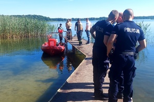 Funkcjonariusze stoją na pomoście znajdującym się na jeziorze