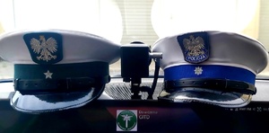 Dwie czapki służbowe lezące na podszybiu radiowozu