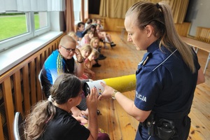 Policjantka tłumaczy dziewczynce działanie odblasków
