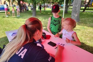 Policjantka rozmawia z dziećmi uczestniczącymi w pikniku