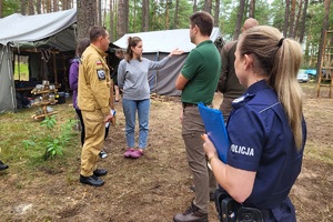 Mundurowi rozmawiają z komendantkami obozu harcerskiego