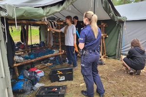 Policjantka sprawdza podobozowisko pod kątem posiadania przedmiotów łatwopalnych