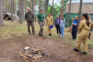 Prowadzący kontrolę mundurowi stoją wokół miejsca wyznaczonego do palenia ogniska