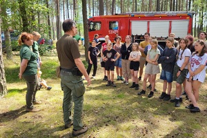 Przed dziećmi stoją pracownicy Nadleśnictwa Dąbrowa