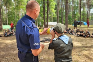 Policjant pokazuje harcerzowi magiczną tubę