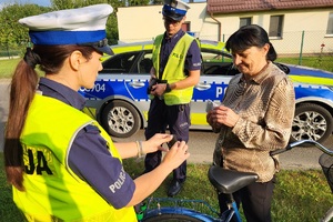 Policjantka wręcza rowerzystce lampkę rowerową w ramach kontroli