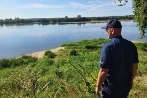 Policjant stoi nad brzegiem Wisły