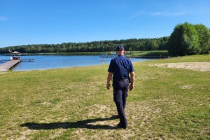 Policjant idzie plażą nad Jeziorem Deczno