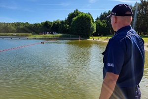 Policjant obserwuje kąpiące się w jeziorze dzieci