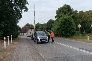 Funkcjonariusze rozmawiają z kierowcą osobówki o bezpieczeństwie na przejeździe kolejowym