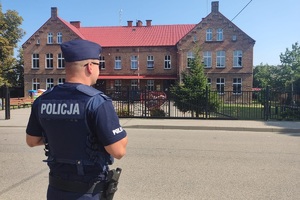 Policjant weryfikuje prawidłowość oznakowania przy szkole