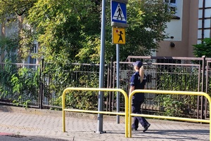 Policjantka sprawdza prawidłowość ustawionego przy przejściu znaku