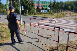 Policjantka sprawdza prawidłowość ustawienia barierek w rejonie przejścia dla pieszych