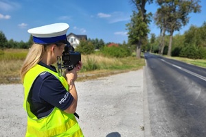 Policjantka mierzy prędkość poruszających się drogą pojazdów