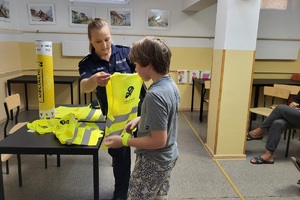 Policjantka wręcza chłopcy kamizelkę odblaskową