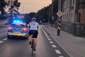 Rowerzysta jedzie drogą w asyście policji