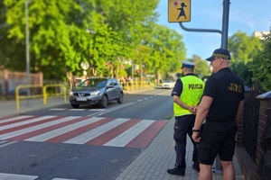 Strażnik miejski wraz z policjantem stoją przy przejściu