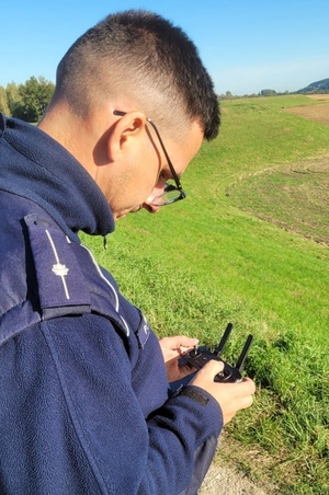 Policjant trzyma w ręku pilota do obsługi drona