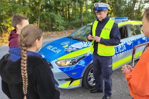 Policjant trzyma w ręku tylną lampkę rowerową