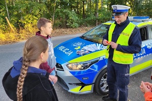 Policjant prezentuje działanie tylnej lampki rowerowej