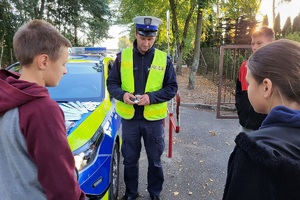 Policjant trzyma w ręku przednią lampkę rowerową