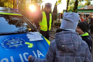 Policjant rozmawia z uczniami przed szkołą