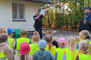 Policjant pokazuje numery alarmowe dzieciom