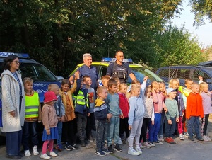 Pamiątkowe zdjęcie dzieci i policjantów na tle radiowozów