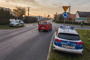 Radiowozy stoją przy poboczy, policjanci kontrolują kierowców