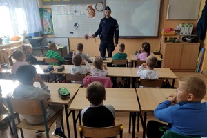 Policjant rozmawia z uczniami w sali lekcyjnej