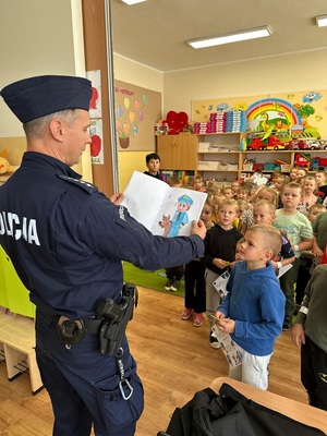 Policjant ogląda laurkę, jaką dostał od predszkolaków