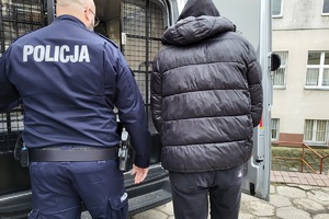 Policjant prowadzi zatrzymanego mężczyznę