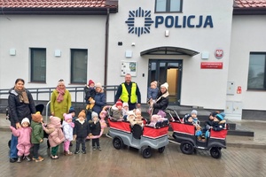 Dzieci, wspólnie z policjantem, pozują do zdjęcia przed posterunkiem