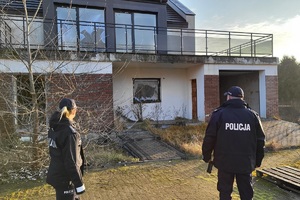 Policjanci obserwują budynek, w którym są powybijane szyby w oknach