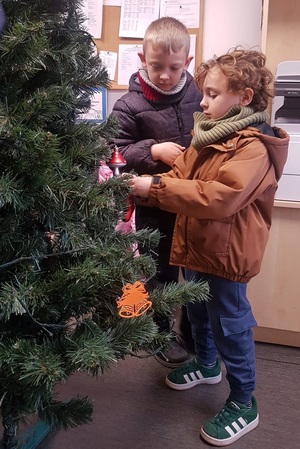 Przedszkolaki zawieszają ozdoby na choinkę