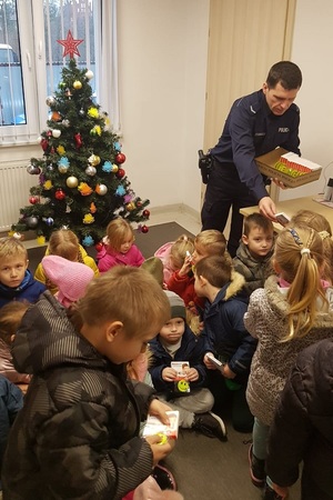 Dzieci otrzymują od policjanta odblaski