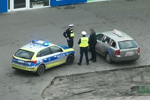 Policjanci rozmawiają z kierowcą na parkingu