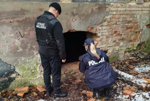 Policjantka i strażnik miejski kontrolują miejsce, gdzie może przebywać bezdomny