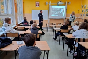 Dzielnicowy w klasie lekcyjnej prowadzi spotkanie z dziećmi