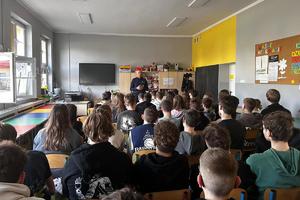 Policjant stoi przed grupą starszych uczniów