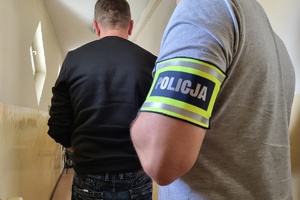 Policjant prowadzi zatrzymanego mężczyznę