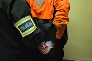 Policjanci prowadzą zatrzymanych sprawców pobicia