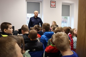 Policjant gości przedszkolaków w posterunku policji, pokazuje radiowóz i edukuje dzieci