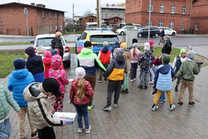 Policjant gości przedszkolaków w posterunku policji, pokazuje radiowóz i edukuje dzieci
